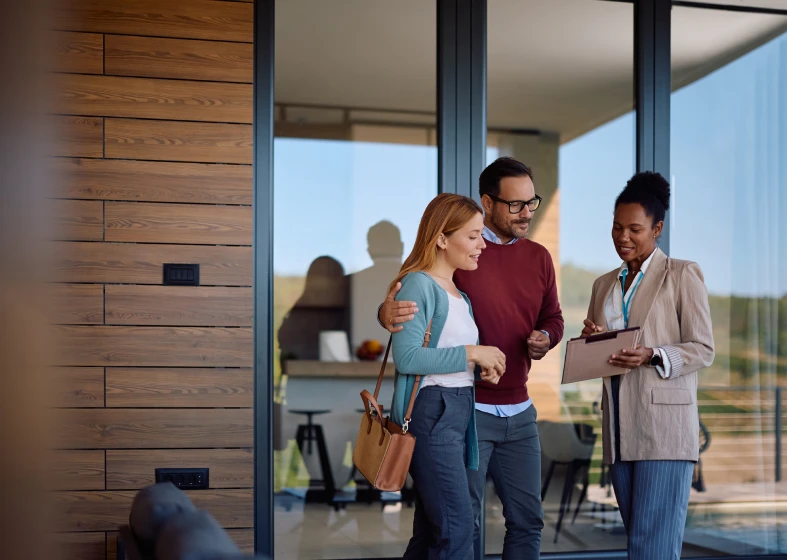 Happy couple with realtor outside house